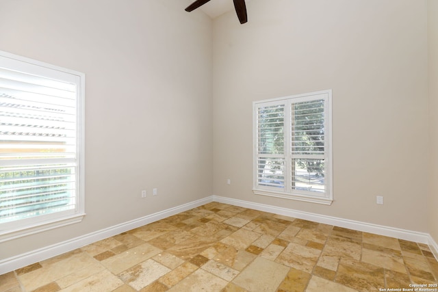 unfurnished room featuring high vaulted ceiling, a ceiling fan, a wealth of natural light, and stone tile flooring