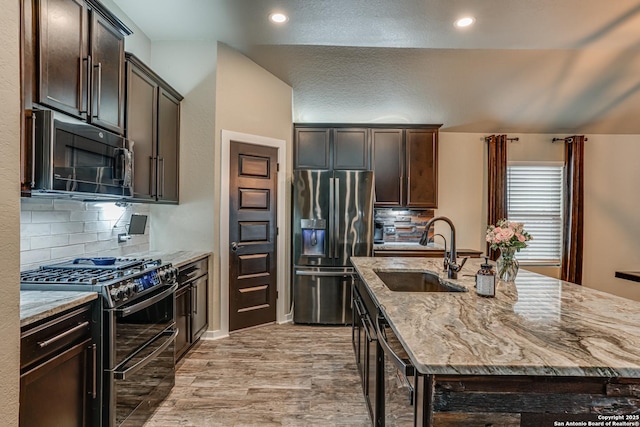 12177 Tower Frst, San Antonio, TX 78253 - kitchen featuring a sink, black microwave, an island with sink, stainless steel fridge with ice dispenser, and range with two ovens