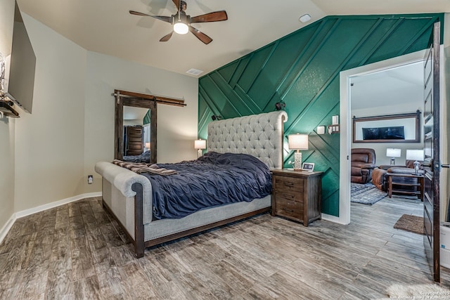 12177 Tower Frst, San Antonio, TX 78253 - bedroom with a barn door, vaulted ceiling, wood finished floors, baseboards, and ceiling fan