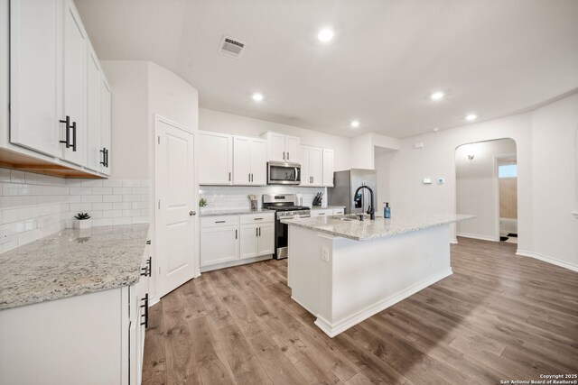 kitchen with visible vents, arched walkways, appliances with stainless steel finishes, and light wood finished floors