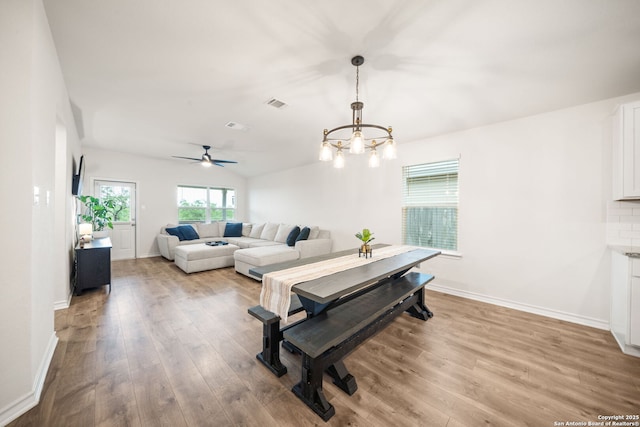 living room with light wood-style flooring, visible vents, baseboards, and ceiling fan with notable chandelier