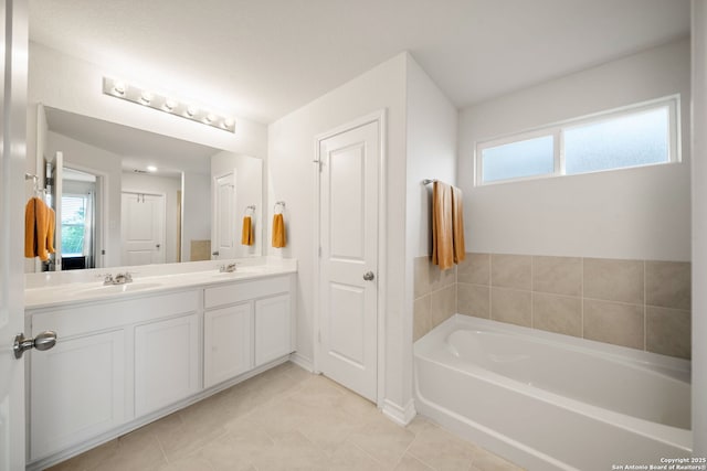 full bathroom featuring double vanity, a bath, tile patterned flooring, and a sink
