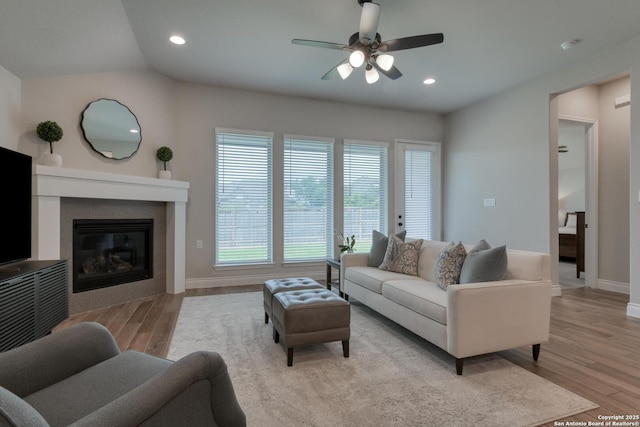 living room with baseboards, recessed lighting, light wood-style floors, ceiling fan, and a tile fireplace