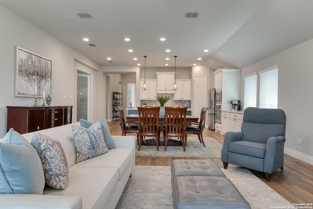 living room with light wood-type flooring, visible vents, and recessed lighting