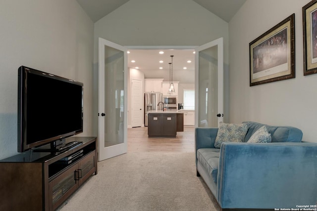 living area featuring recessed lighting, vaulted ceiling, light colored carpet, and french doors
