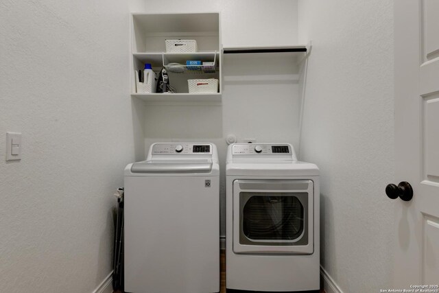 washroom with baseboards, independent washer and dryer, and laundry area