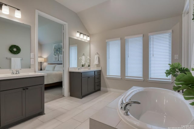 bathroom featuring vaulted ceiling, a sink, ensuite bathroom, a bath, and two vanities