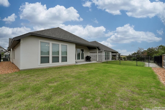 back of house with a lawn, fence, a shingled roof, and stucco siding