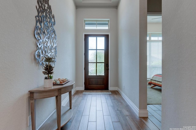 entrance foyer with baseboards, wood finished floors, and a textured wall