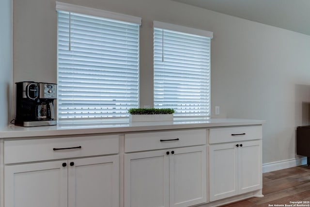 room details with white cabinets, baseboards, light wood-style flooring, and light countertops