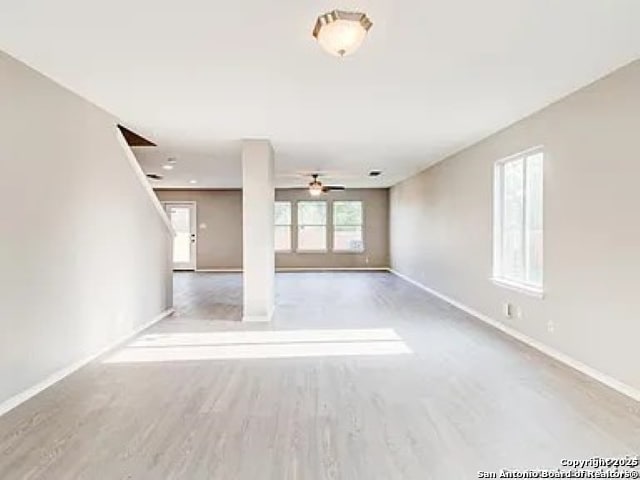 unfurnished living room featuring baseboards, wood finished floors, and a ceiling fan