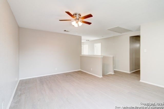 empty room with attic access, a ceiling fan, visible vents, baseboards, and wood finished floors