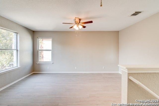 unfurnished room featuring visible vents, ceiling fan, baseboards, and light wood-type flooring