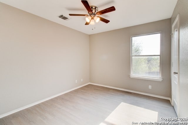 empty room featuring plenty of natural light, ceiling fan, wood finished floors, and visible vents