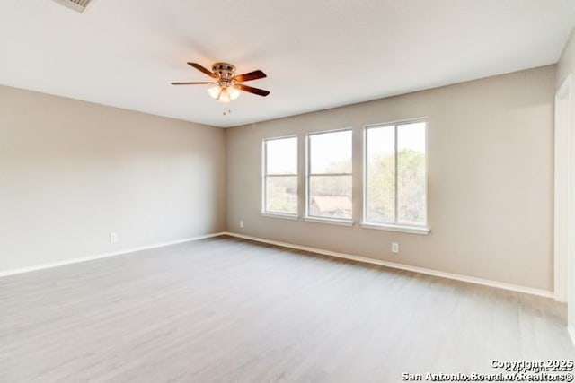 empty room featuring light wood finished floors, a ceiling fan, and baseboards