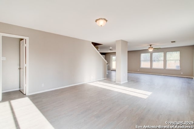 unfurnished living room with wood finished floors, a ceiling fan, and baseboards