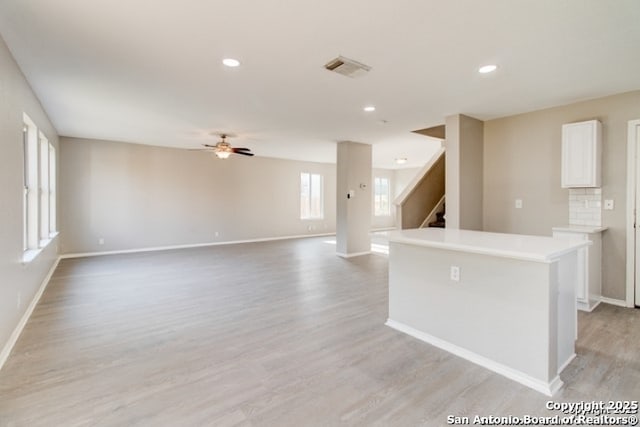 kitchen with baseboards, light wood finished floors, white cabinetry, a center island, and a ceiling fan