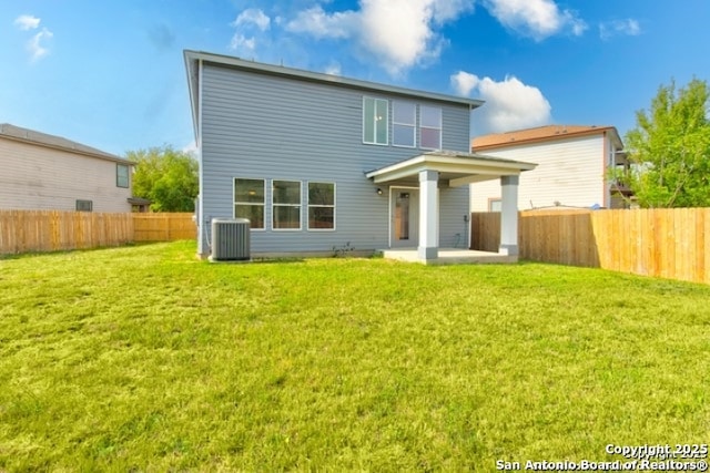 rear view of house with a fenced backyard, a yard, and a patio area