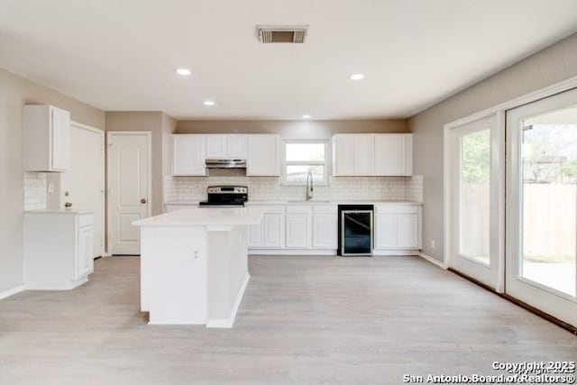 kitchen featuring a sink, wine cooler, stainless steel electric range oven, visible vents, and backsplash