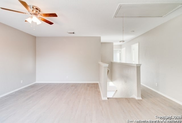 spare room featuring visible vents, ceiling fan, baseboards, attic access, and light wood finished floors