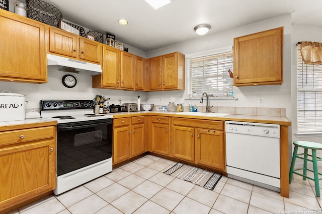 kitchen with electric range, under cabinet range hood, white dishwasher, a sink, and tile countertops