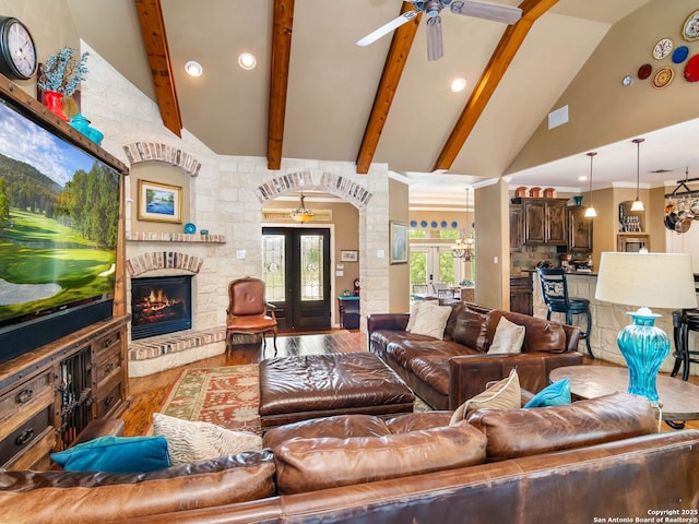 living area featuring a fireplace, wood finished floors, a ceiling fan, and beamed ceiling