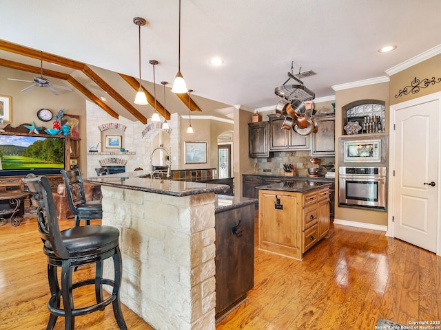 kitchen with crown molding, a ceiling fan, stainless steel appliances, and a center island with sink