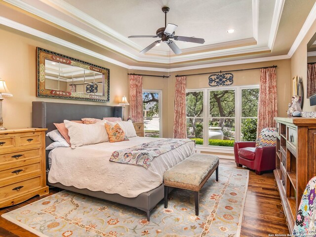 bedroom with recessed lighting, wood finished floors, ornamental molding, ceiling fan, and a tray ceiling