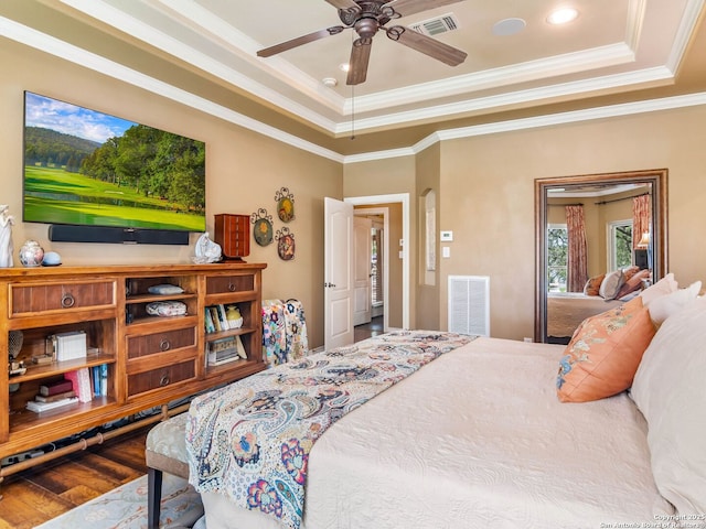 bedroom with visible vents, a raised ceiling, ornamental molding, and wood finished floors