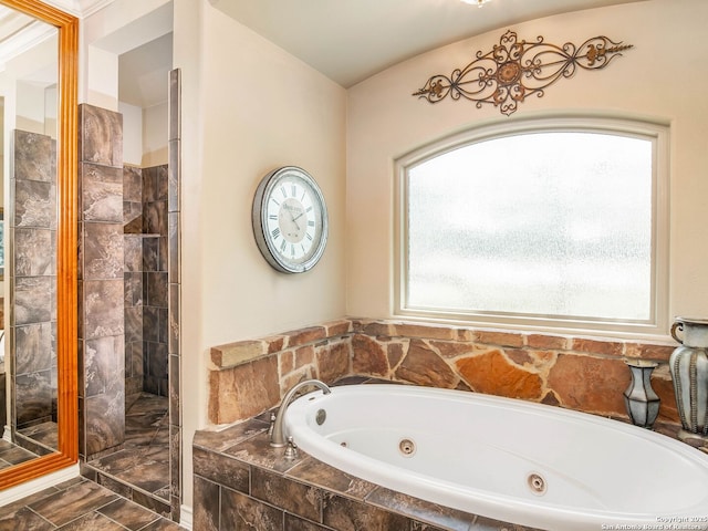 bathroom featuring a tub with jets, a healthy amount of sunlight, and a tile shower