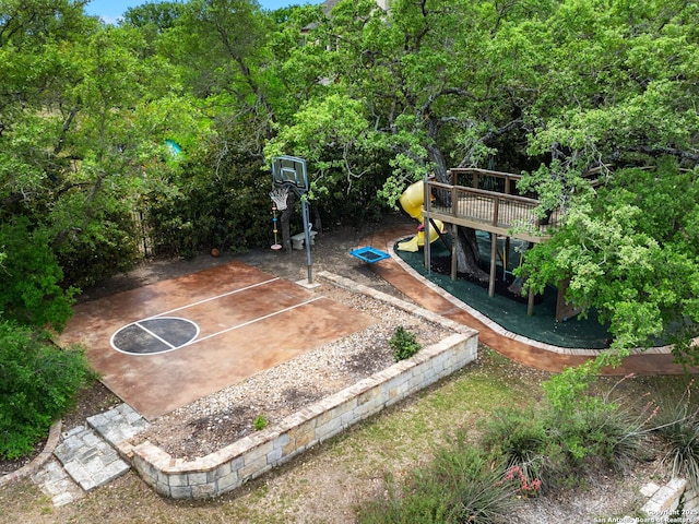 view of sport court featuring a playground and basketball hoop