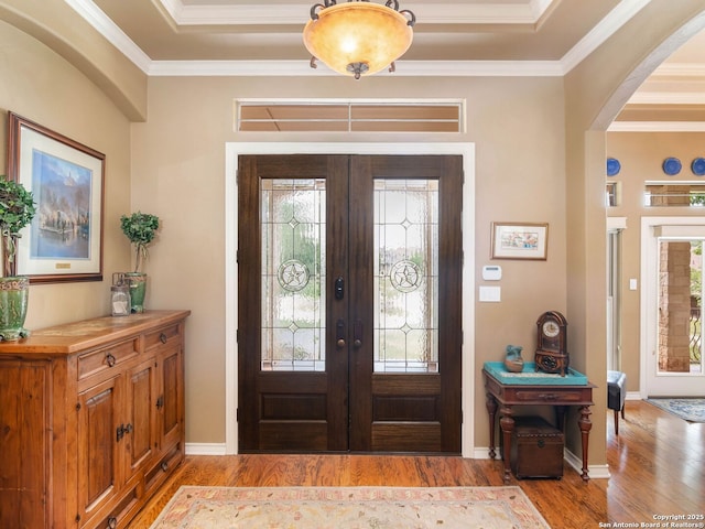 entryway with baseboards, ornamental molding, arched walkways, french doors, and wood finished floors