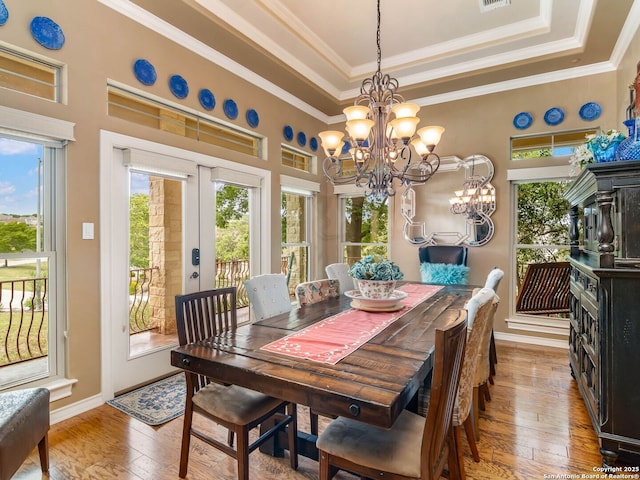dining room featuring an inviting chandelier, a raised ceiling, baseboards, french doors, and hardwood / wood-style flooring