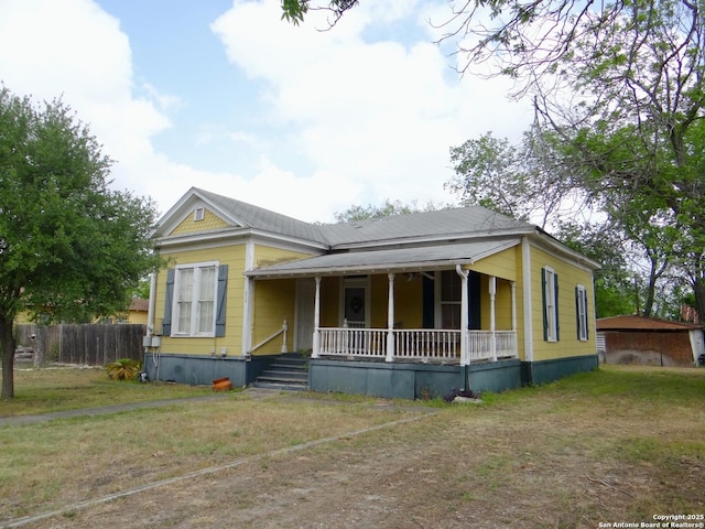 view of front of home featuring covered porch, fence, and a front yard