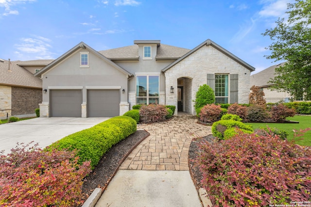 traditional home featuring an attached garage, stucco siding, concrete driveway, and stone siding
