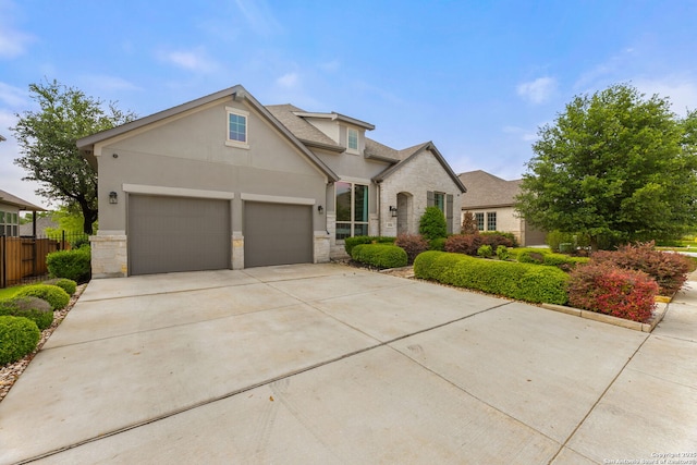 traditional-style home featuring stucco siding, concrete driveway, an attached garage, and stone siding