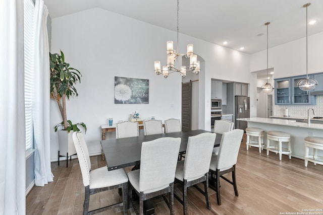 dining area with wood finished floors, high vaulted ceiling, a chandelier, and recessed lighting