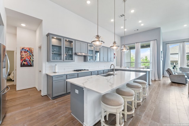 kitchen featuring hardwood / wood-style flooring, a wealth of natural light, a sink, gray cabinetry, and visible vents