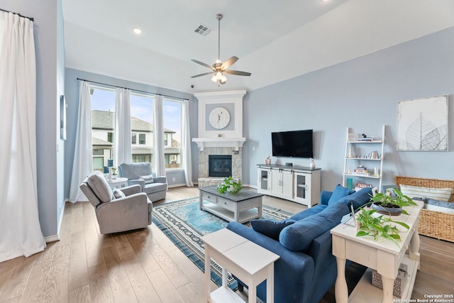 living room with wood finished floors, a ceiling fan, and a glass covered fireplace
