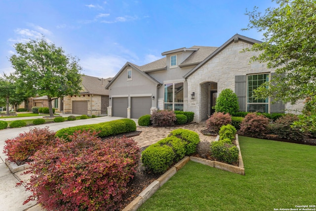 view of front of home with stucco siding, stone siding, a front lawn, concrete driveway, and an attached garage