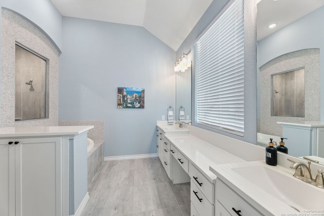 bathroom featuring lofted ceiling, a tile shower, double vanity, and a sink