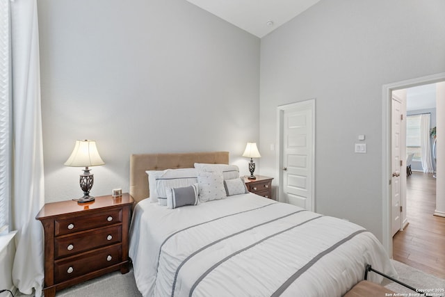 bedroom featuring high vaulted ceiling and wood finished floors