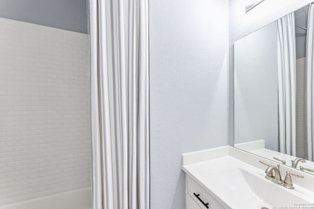 bathroom featuring a textured wall, tub / shower combination, and vanity