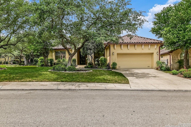 mediterranean / spanish-style house featuring a front lawn, stucco siding, a tiled roof, concrete driveway, and an attached garage