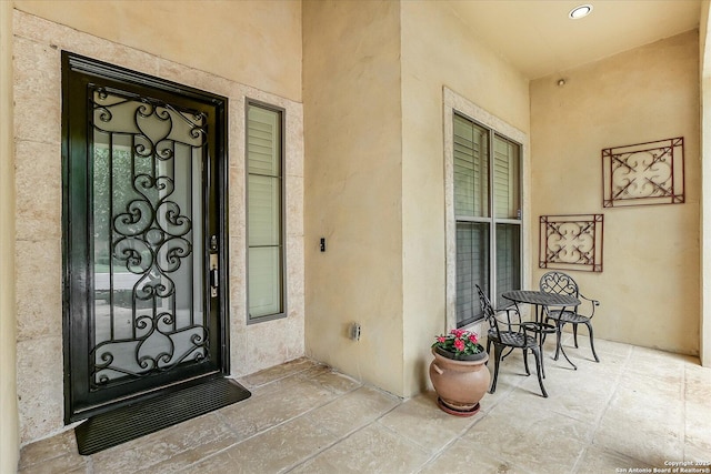 view of exterior entry featuring a porch and stucco siding