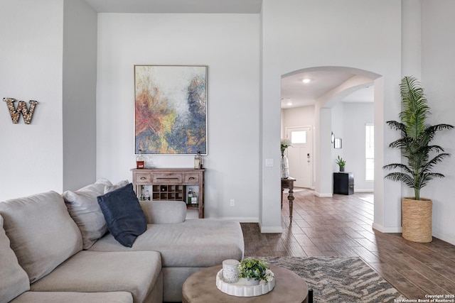 living room with wood finished floors, baseboards, and arched walkways