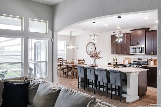 kitchen featuring decorative backsplash, a kitchen bar, open floor plan, appliances with stainless steel finishes, and wood finished floors