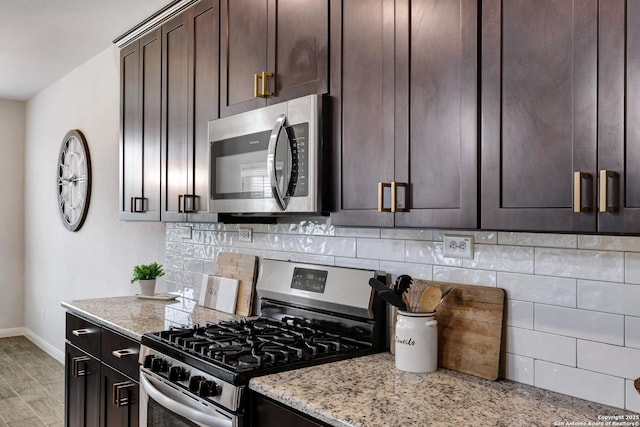 kitchen featuring dark brown cabinetry, appliances with stainless steel finishes, decorative backsplash, and baseboards