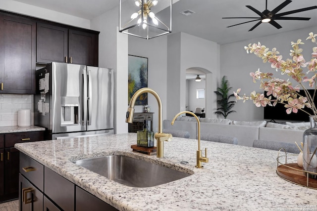 kitchen with a sink, stainless steel fridge, ceiling fan, visible vents, and arched walkways
