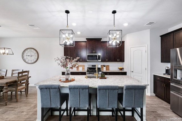 kitchen featuring a breakfast bar area, tasteful backsplash, visible vents, and stainless steel appliances